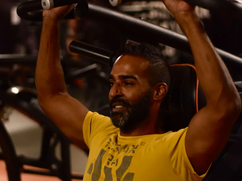 Lid van ClubFit traint op een krachtapparaat in de fitnesszaal